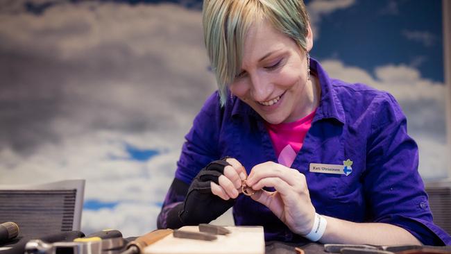 A smiling person creating a keychain at a workshop