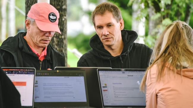 Two persons monitoring  on laptop screens