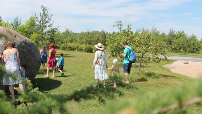 Families walking in the park on a sunny day.