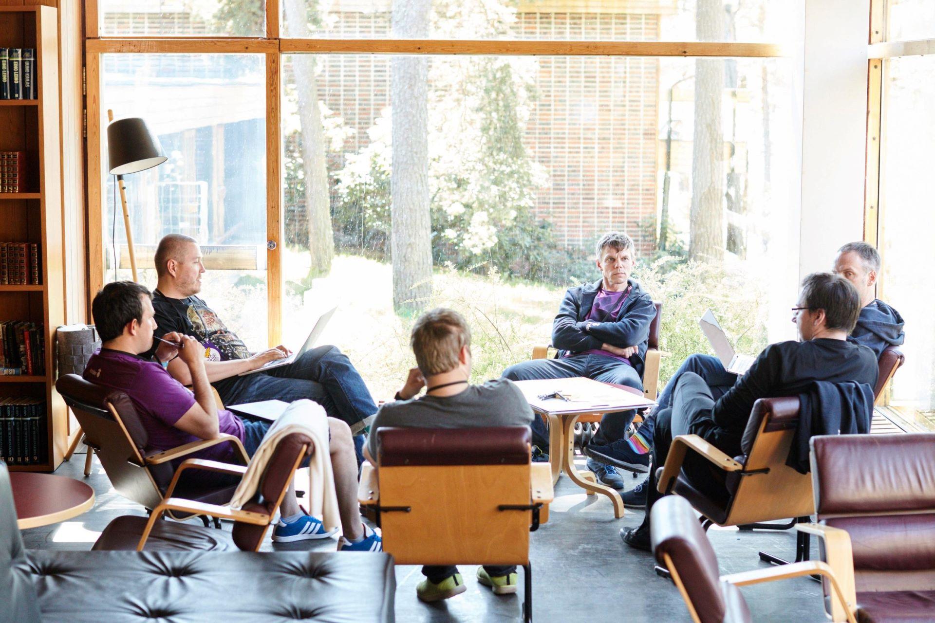 Ryhmä Wunderin kehittäjiä istumassa ja keskustelemassa yhdessä aulatilan pöydän ympärillä.