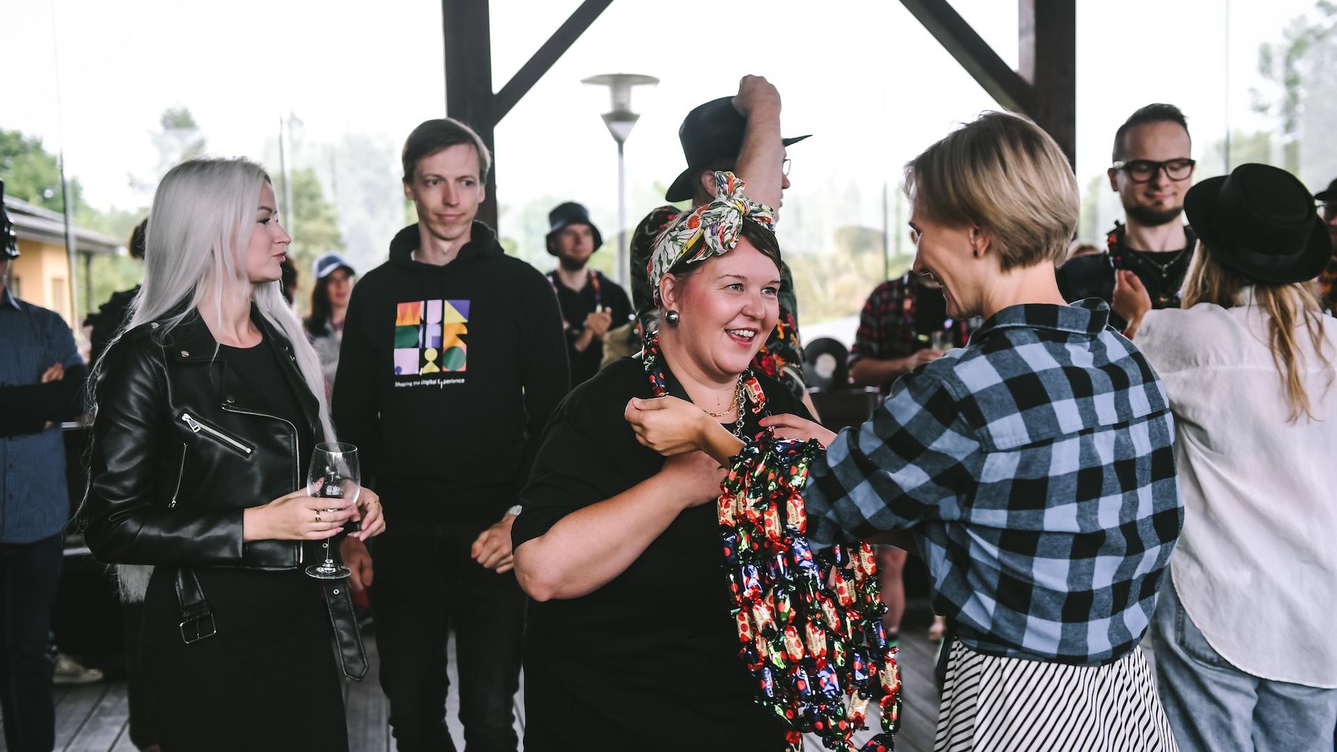 Person in colorful clothas receiving a candy lei while others watching