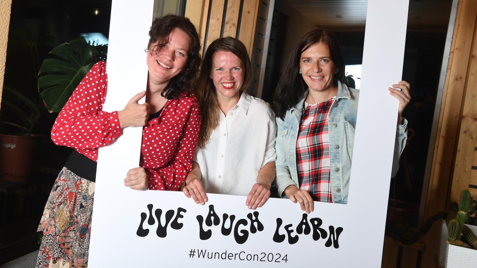 Three persons posing with a photo frame