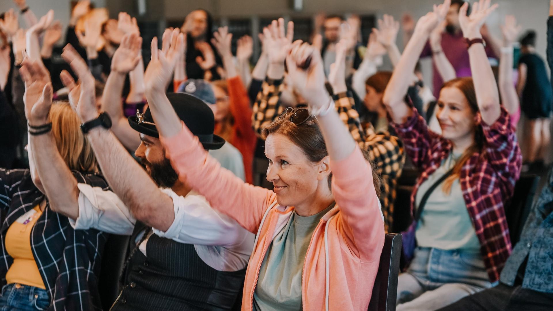 People sitting indoors with raised hands