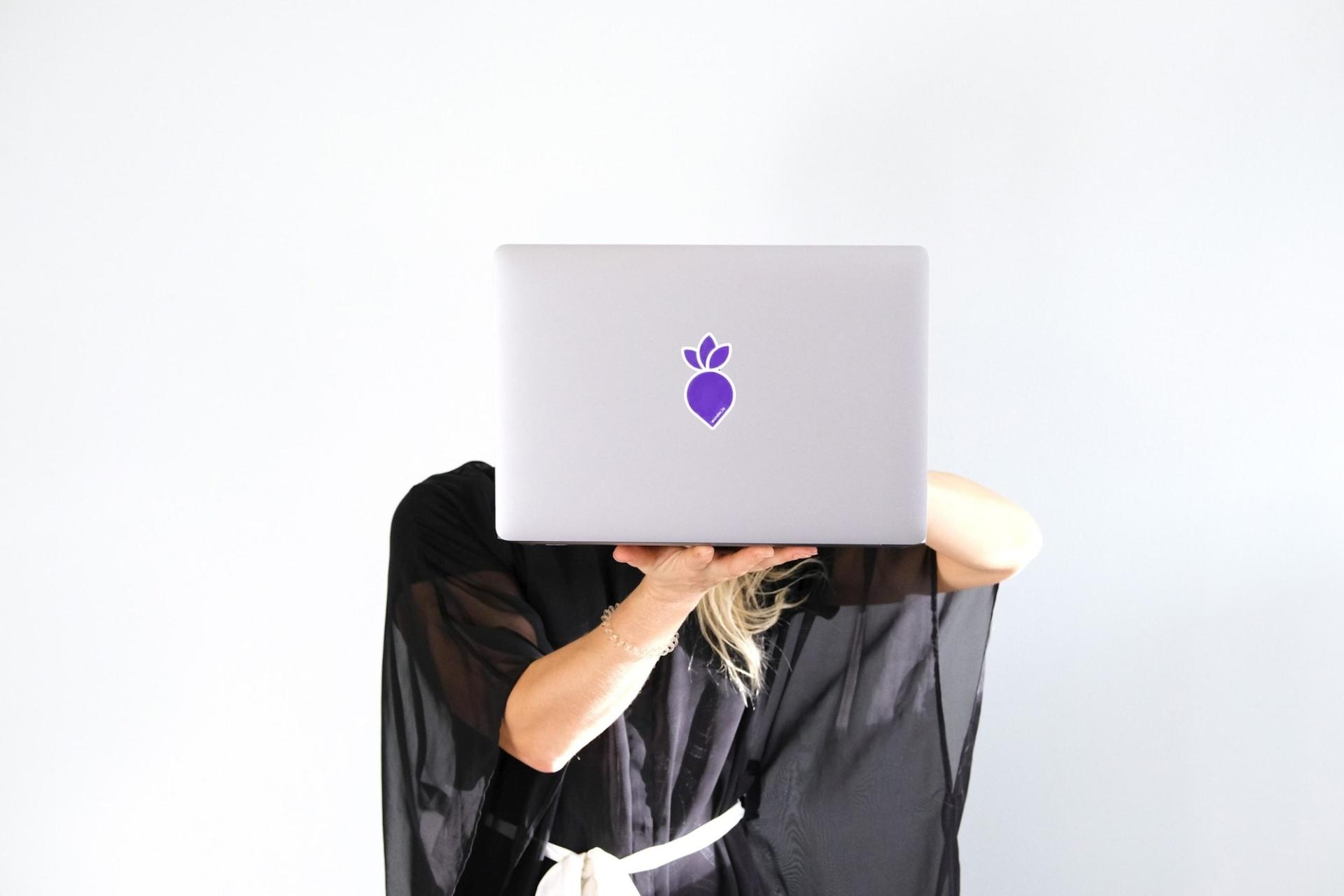 Person holding laptop with one hand in front of they face