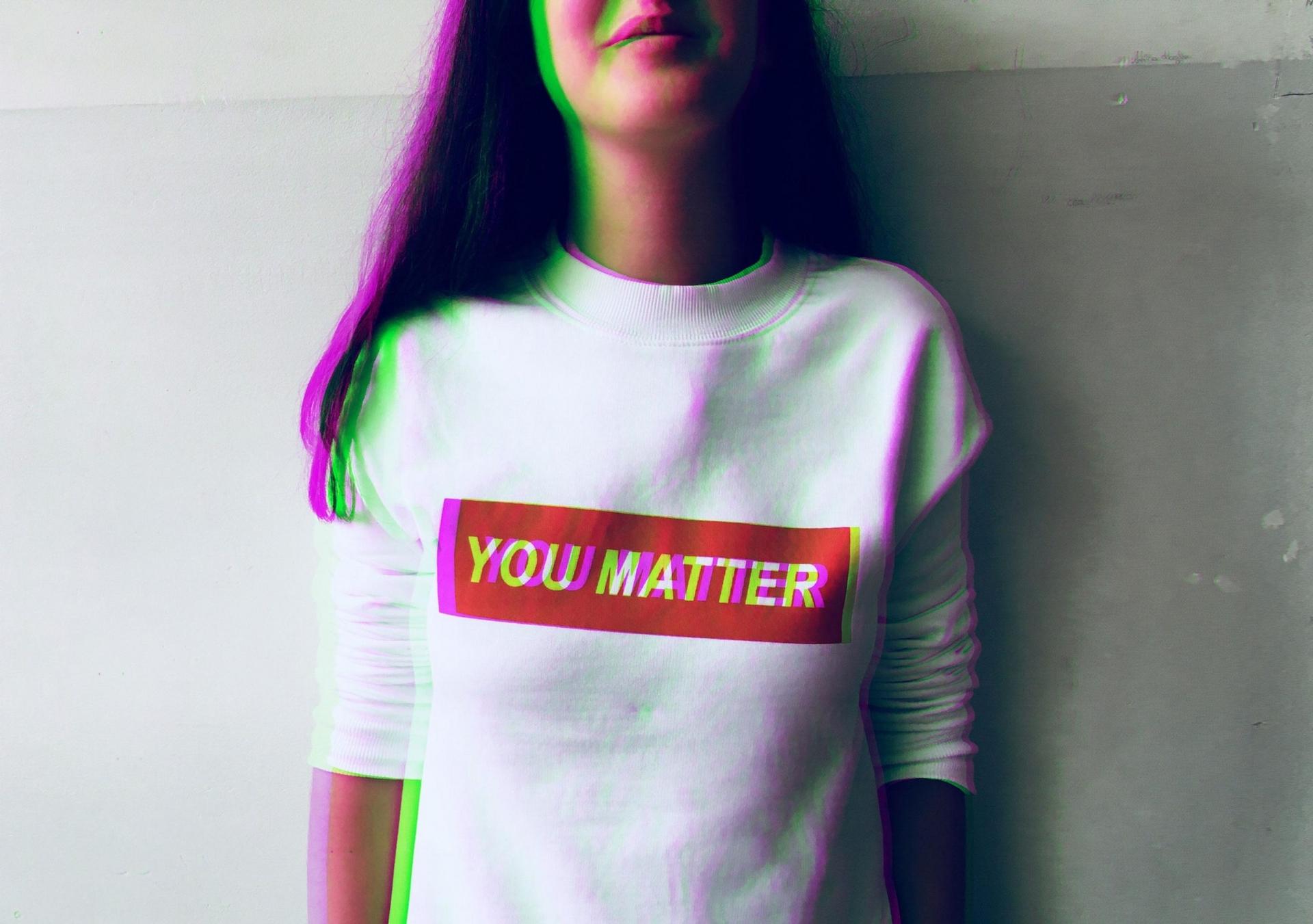 A person wearing a white t-shirt with text - You matter